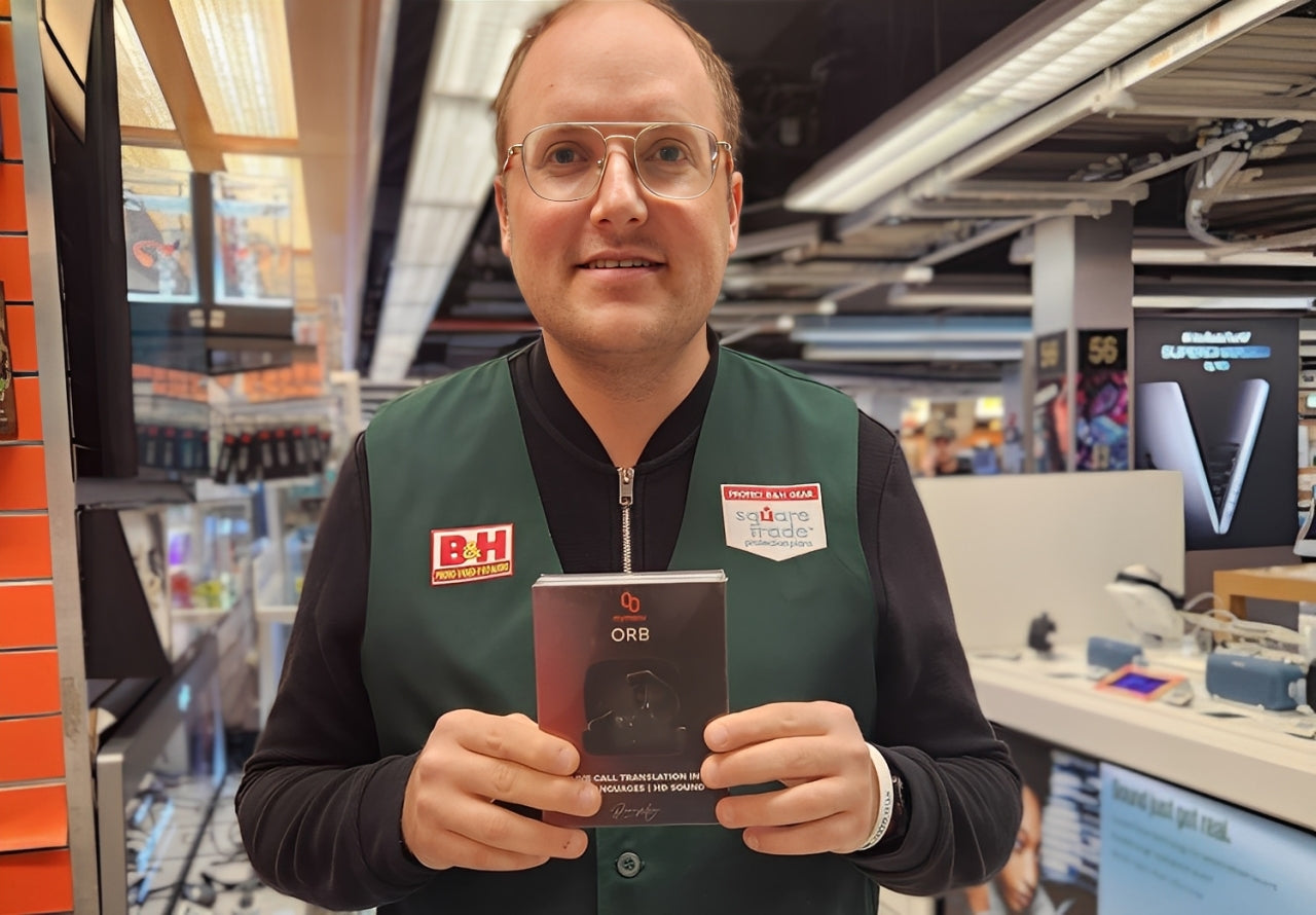 Man holding ORB real-time translation earbuds box in electronics store, showcasing AI language translator headphones