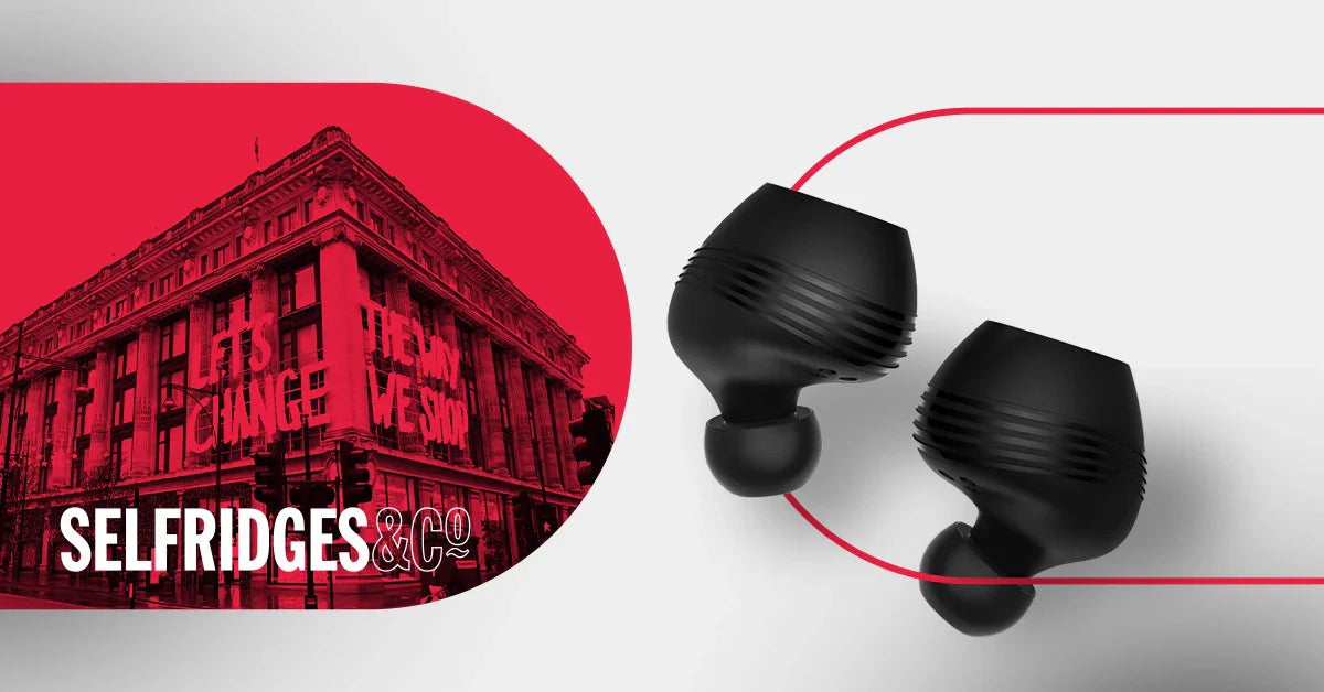 Black translation earbuds with red Selfridges & Co building background, for real-time language translation.